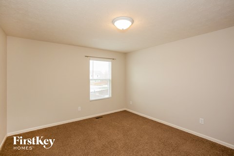 the spacious living room of a home with carpet and a window