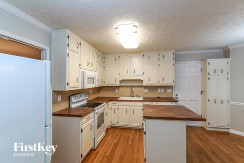 A kitchen with wooden floors and white cabinets.