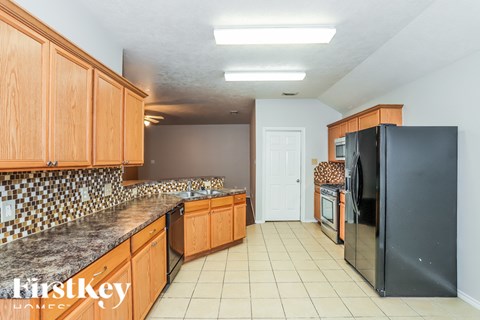 A kitchen with wooden cabinets and a black refrigerator.