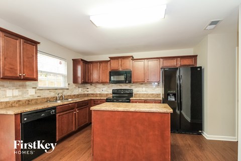 A kitchen with wooden cabinets and a black refrigerator.