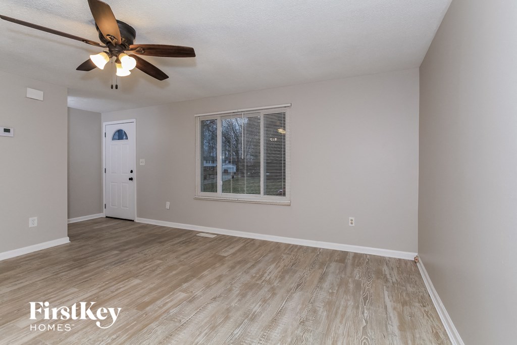 the living room of an empty house with a ceiling fan