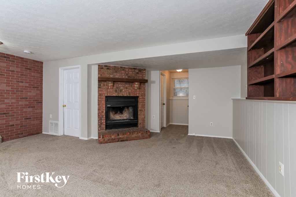 a living room with a brick fireplace and wooden shelves