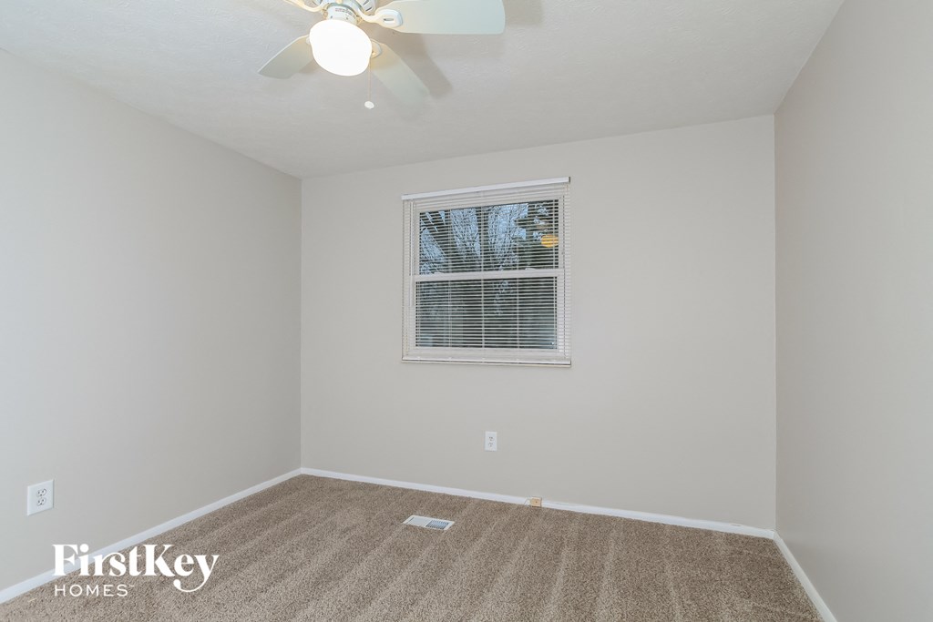 the living room of an empty house with carpet and a ceiling fan