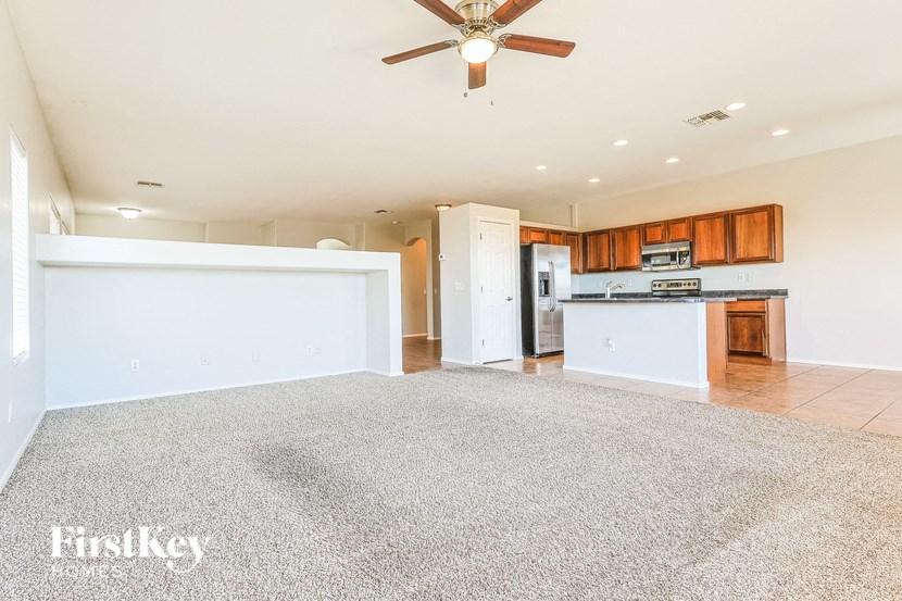 A spacious room with a carpeted floor and a ceiling fan.