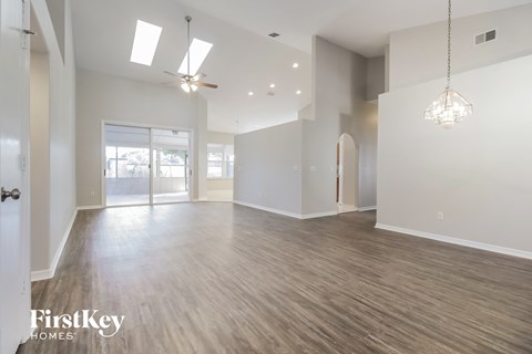 A spacious room with wooden floors and a ceiling fan.