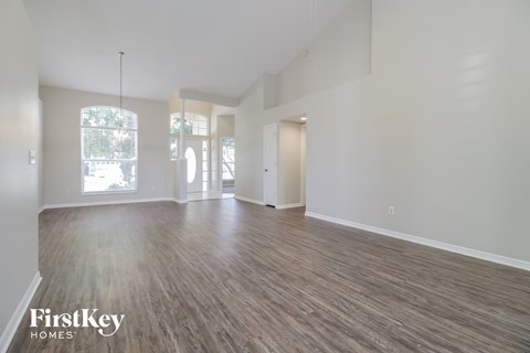 A spacious room with wooden flooring and white walls.