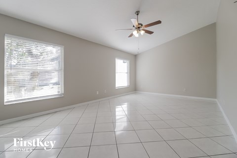 A spacious room with a ceiling fan and a window with blinds.