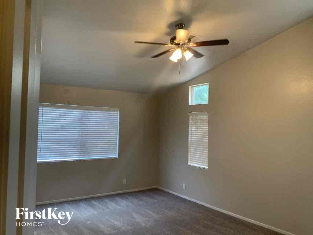 an empty living room with a ceiling fan and a window