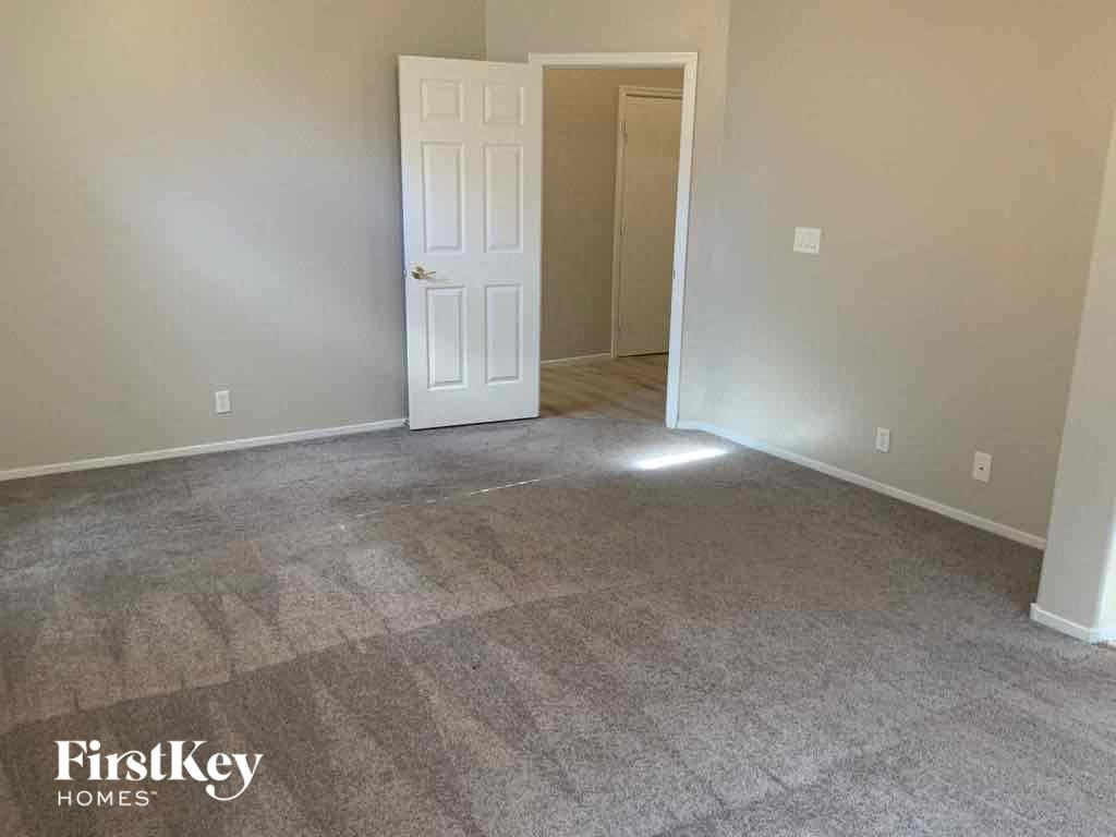 a carpeted living room with a white door and gray carpet