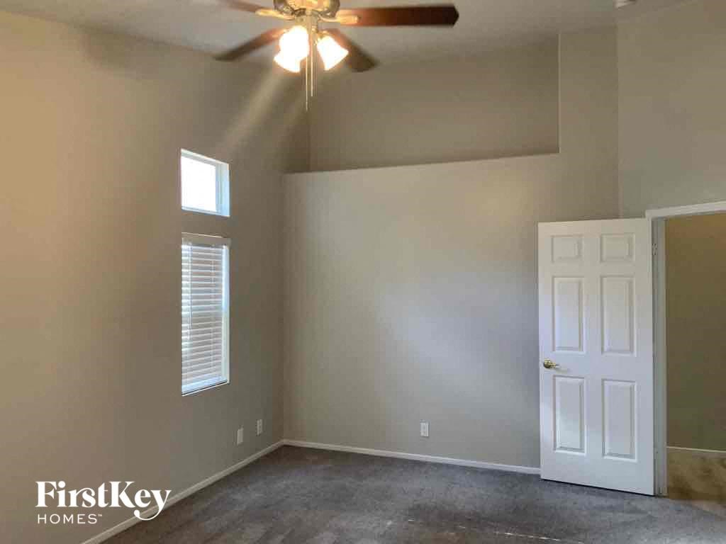 an empty living room with a ceiling fan and a white door