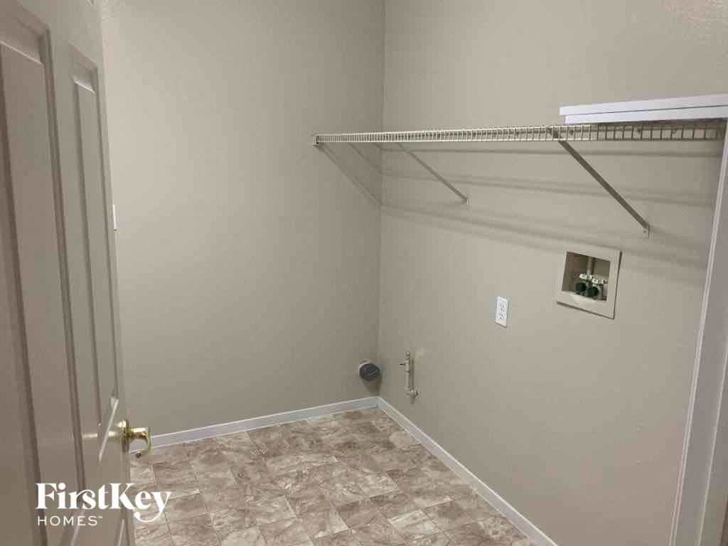 a walk in closet in a white room with a shelf on the wall