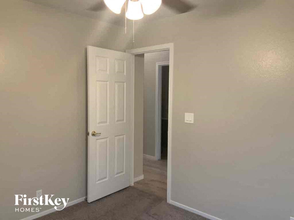 an empty bedroom with a closet and a white door and a ceiling fan