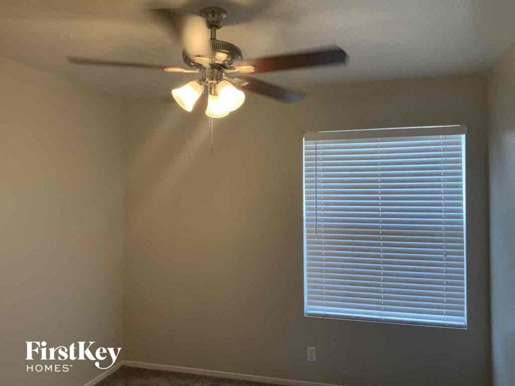 a room with a ceiling fan and a window with a blind