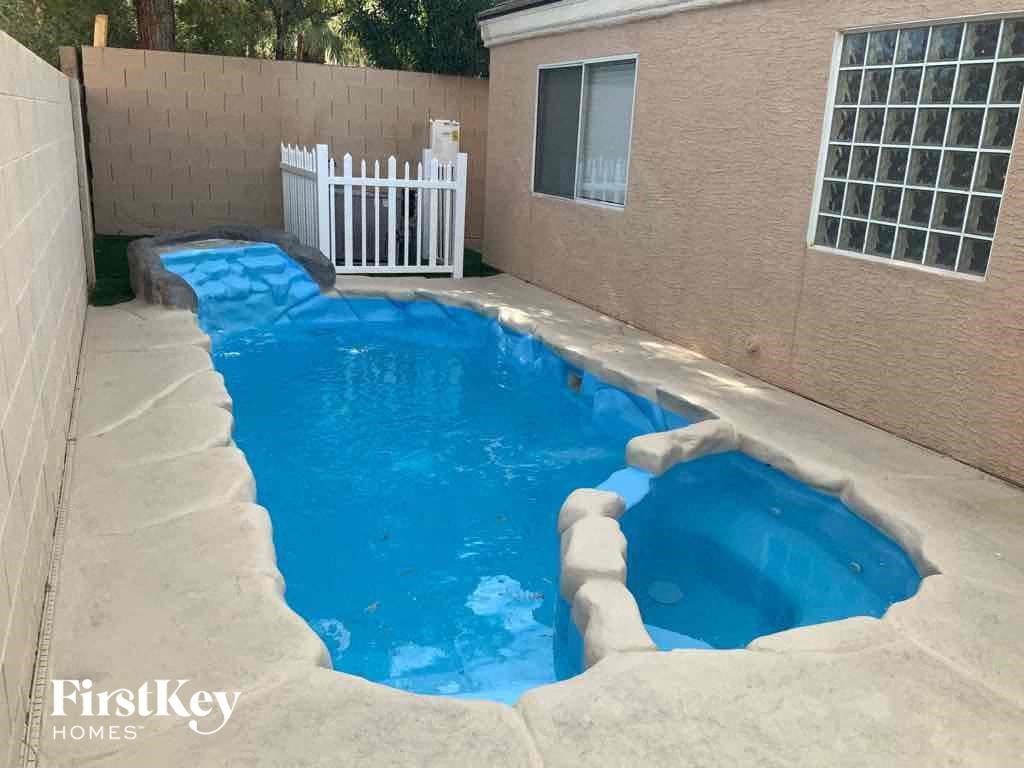 a swimming pool in the backyard of a house with a white fence