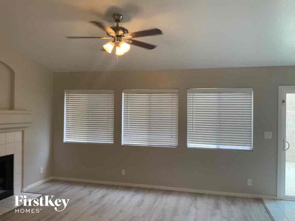 a living room with three windows and a ceiling fan