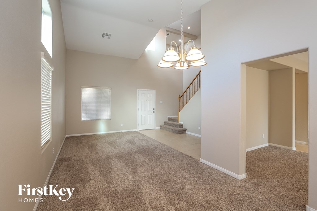 a spacious living room with carpeted flooring and a staircase