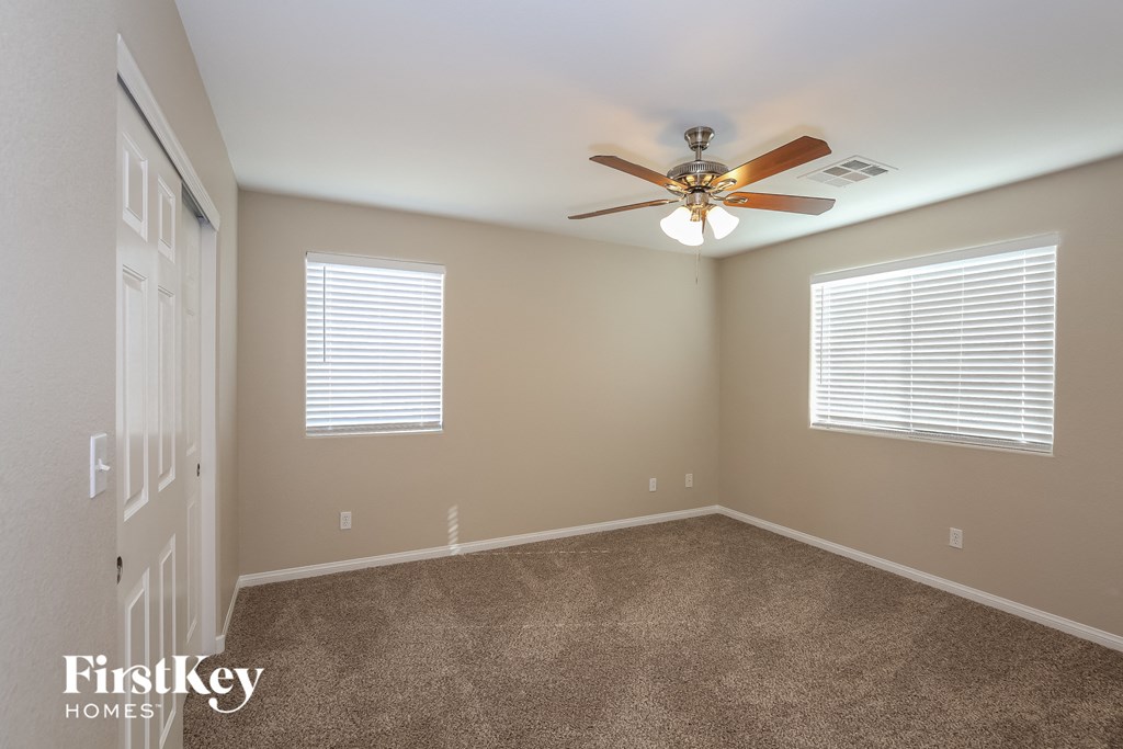 a bedroom with carpet and a ceiling fan and two windows