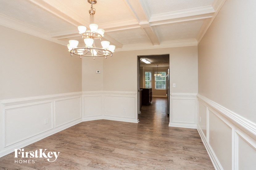 A large empty room with a chandelier and wood flooring.