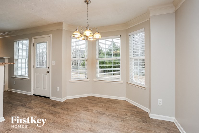 A room with a light brown wooden floor and a chandelier hanging from the ceiling.