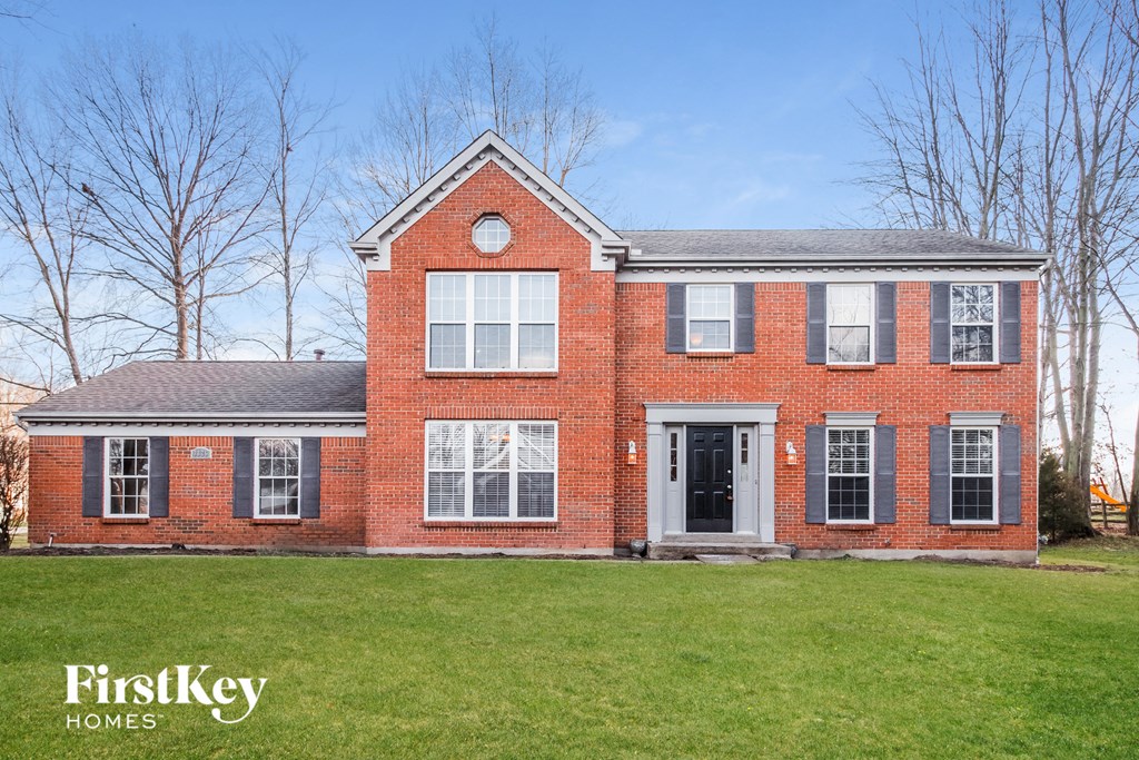 a red brick house with a green lawn in front of it