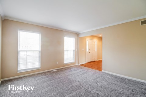 a living room with a rug and two windows