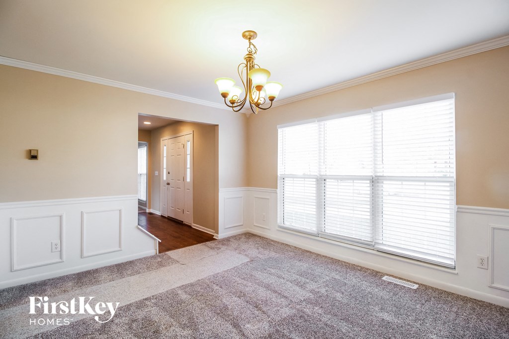 a dining room with a large window and a rug and a chandelier