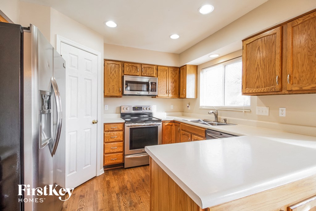 a kitchen with wooden cabinets and stainless steel appliances and a white counter top