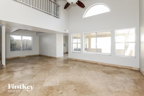 A spacious room with a fan and large windows.