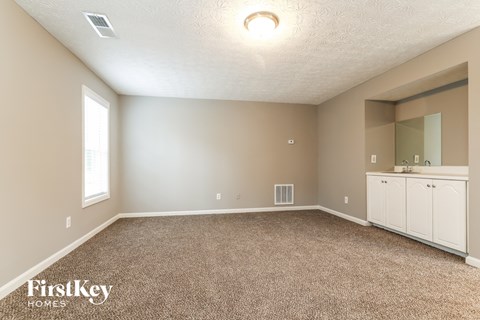 an empty room with carpet and a sink and a mirror