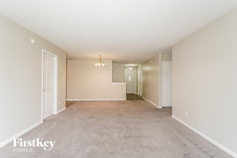 a spacious living room and dining room with white walls and carpet
