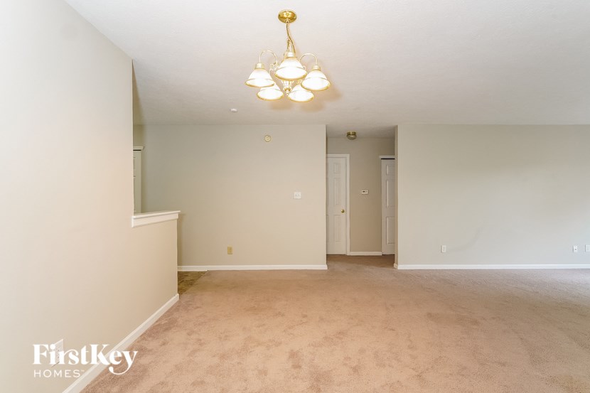 a living room and dining room with carpet and a chandelier