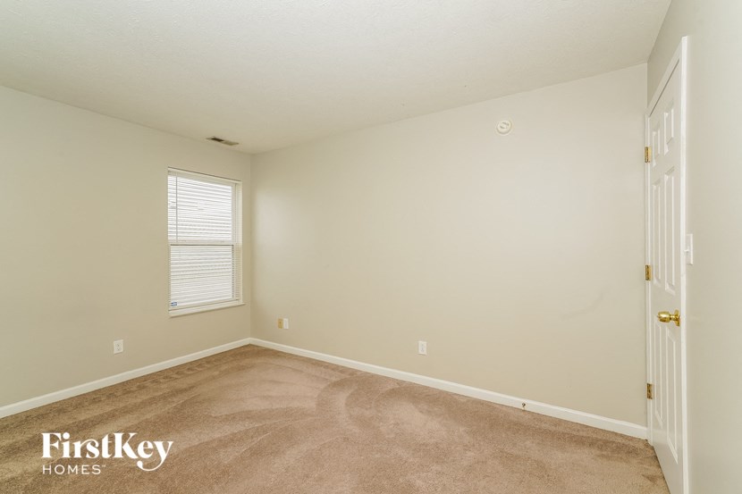 the bedroom of a house with a carpeted floor and a window