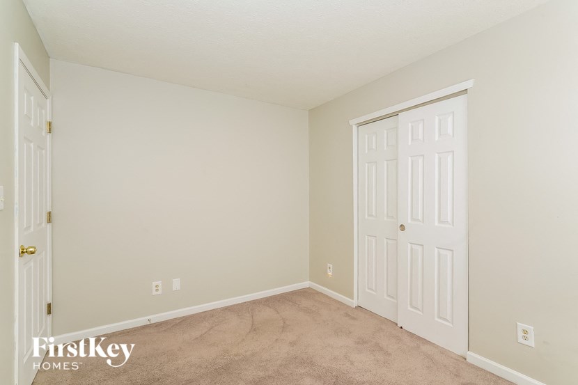 a bedroom with a white door and a carpeted floor