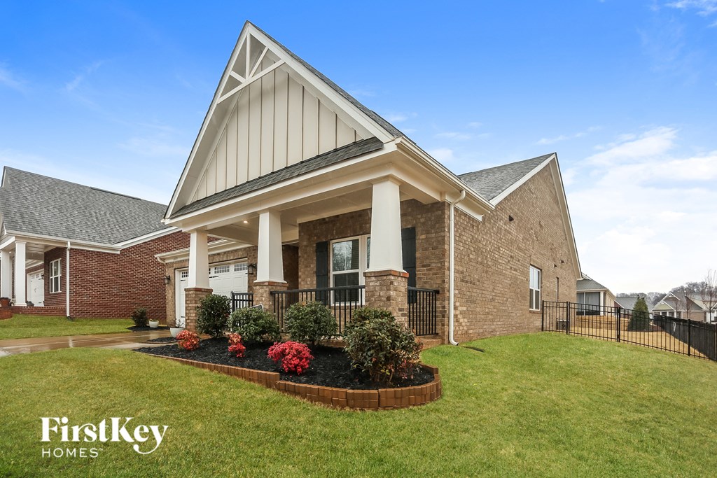 A brick house with a black fence in front.