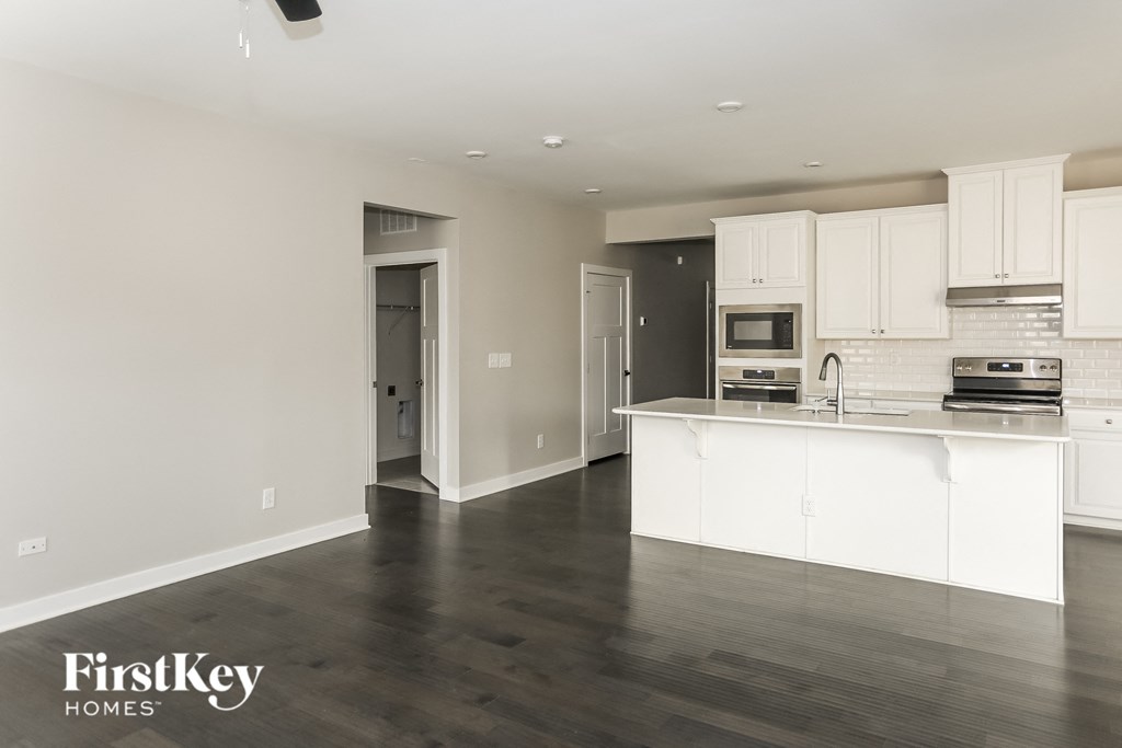 A kitchen with white cabinets and a wooden floor.