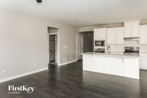 A kitchen with white cabinets and a wooden floor.
