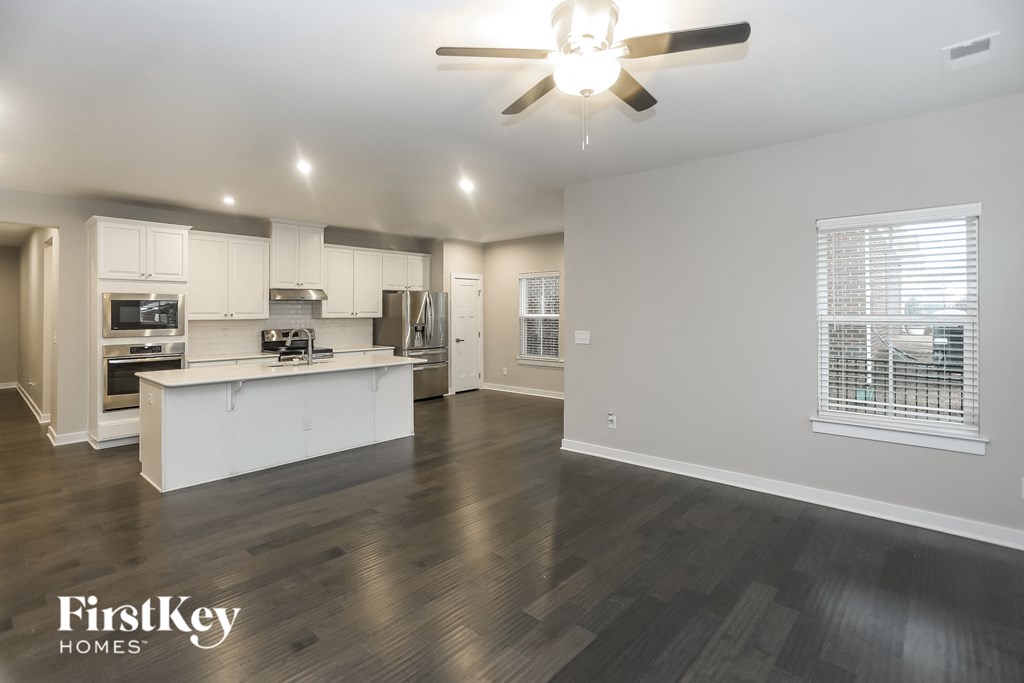 A spacious kitchen and living room with a wood floor and a ceiling fan.