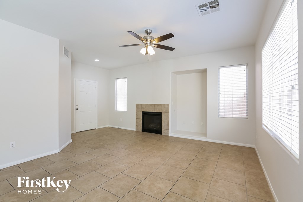 an empty living room with a ceiling fan and a fireplace