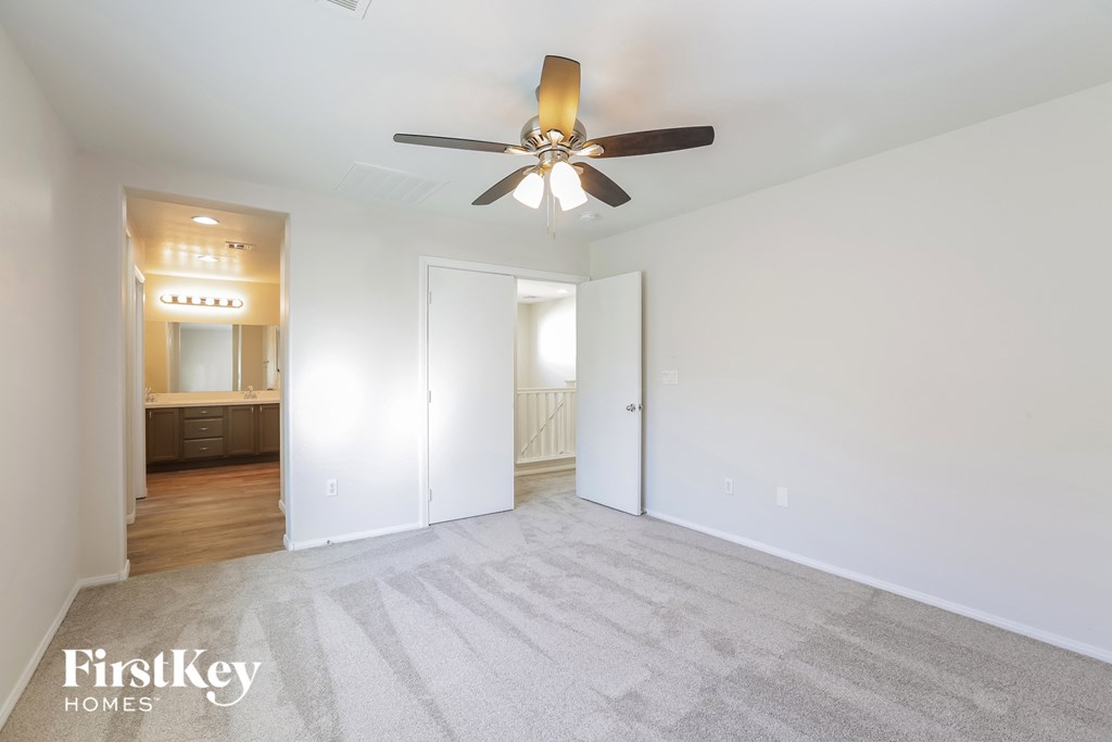an empty living room with a ceiling fan and a door to a bathroom