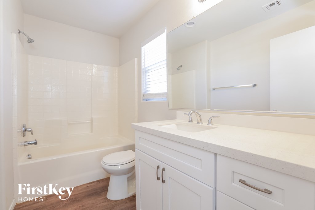 a bathroom with white cabinets and a white toilet and tub and a sink