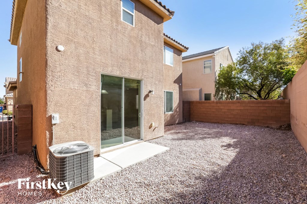 a side view of a brick house with a patio and a trash can