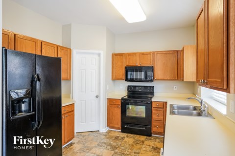 a kitchen with wooden cabinets and a black refrigerator