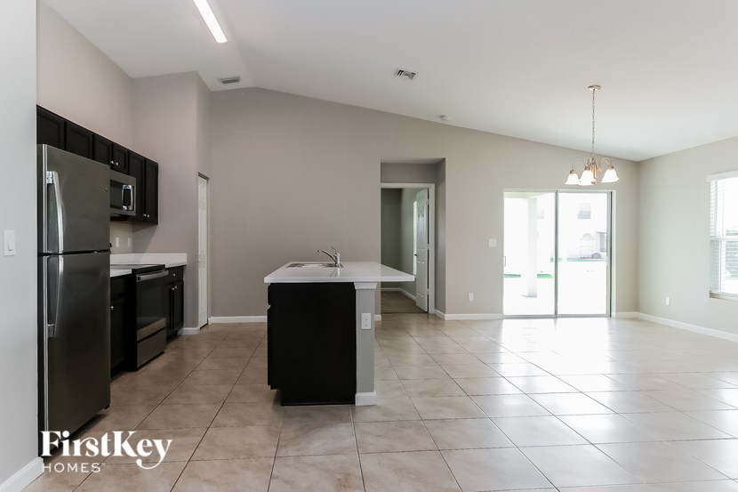 A kitchen with a black fridge and microwave, a black island, and a white countertop.