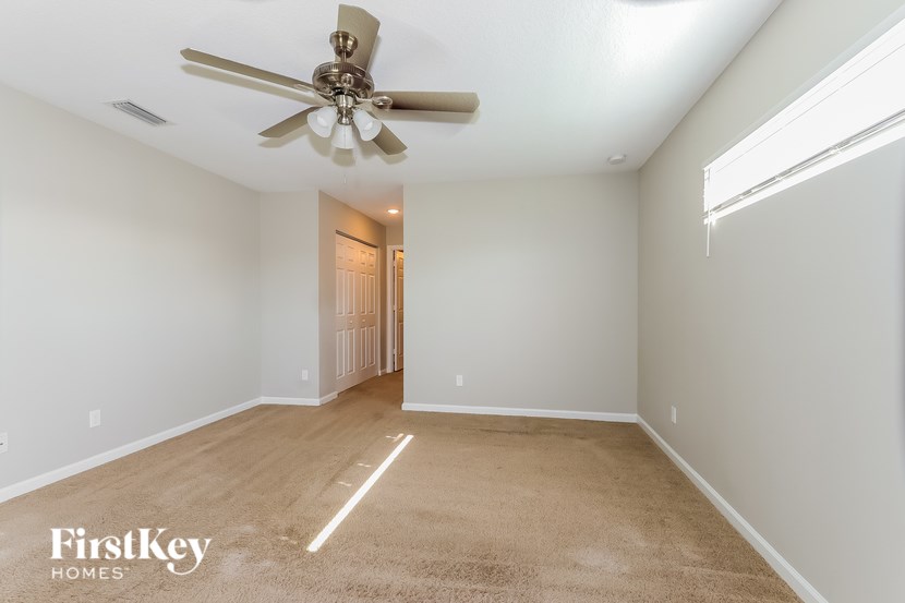 A spacious room with a ceiling fan and a carpeted floor.