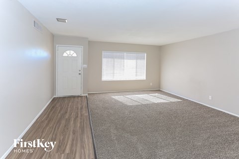 a spacious living room with white walls and wood flooring