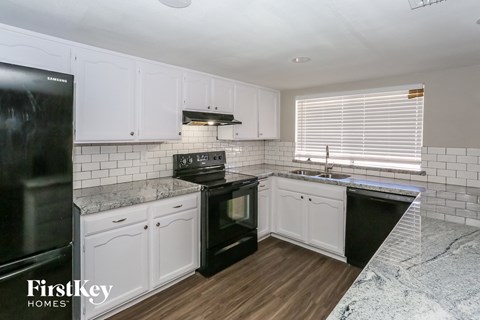 a white kitchen with black appliances and white cabinets