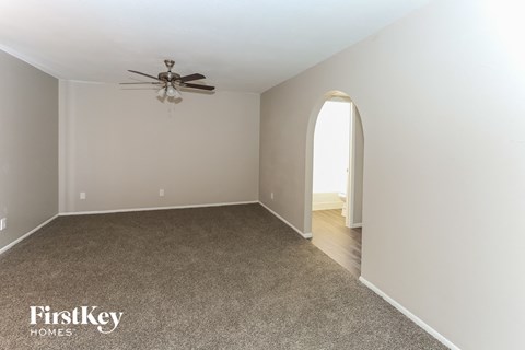 a living room with a carpet and a ceiling fan