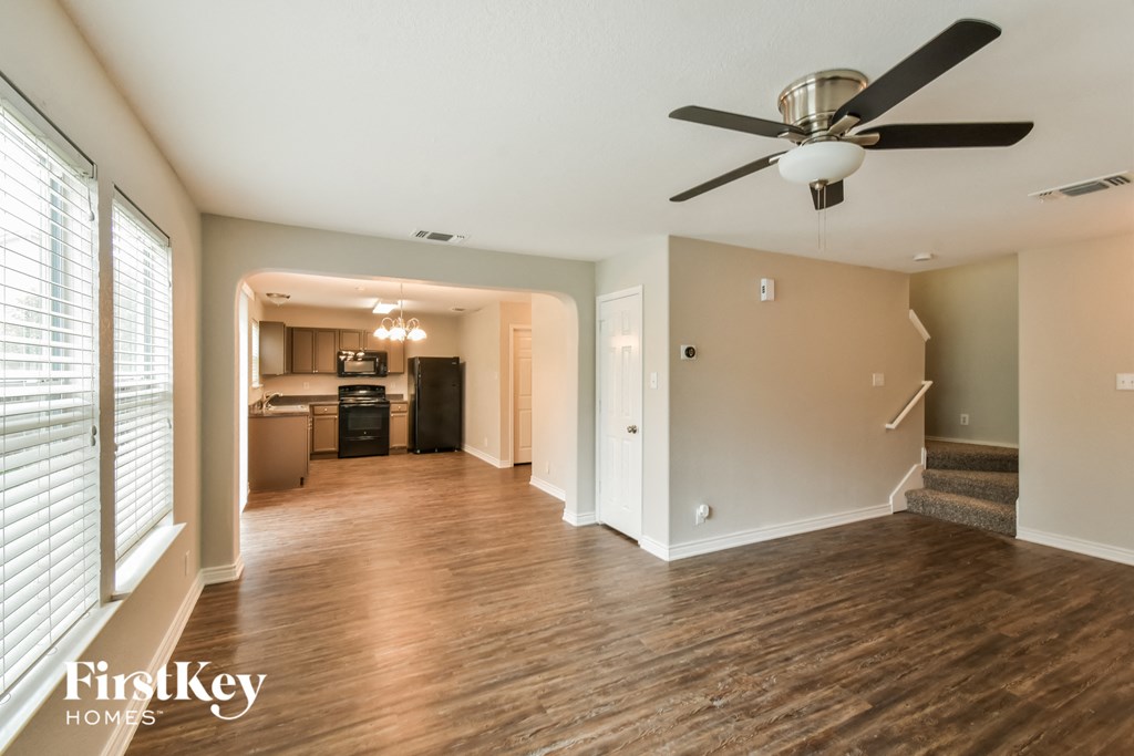 an empty living room and kitchen with a ceiling fan