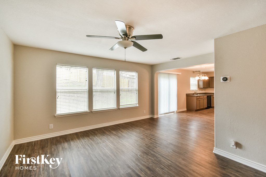 an empty living room with wood floors and a ceiling fan