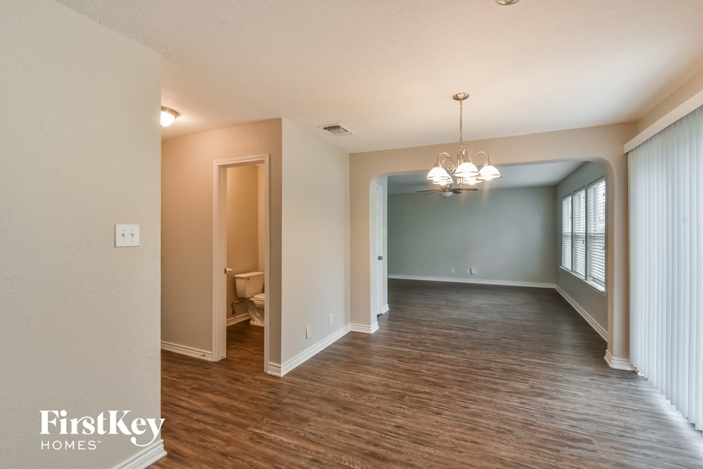 the living room and dining room of an empty house with wood flooring